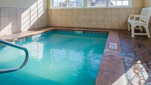 Ein Innenpool mit klarem Wasser, gefliesten Wänden und einer Sitzbank am Beckenrand.