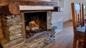 A stone fireplace with a rustic design, a decorative log on top, and a metal firebox.