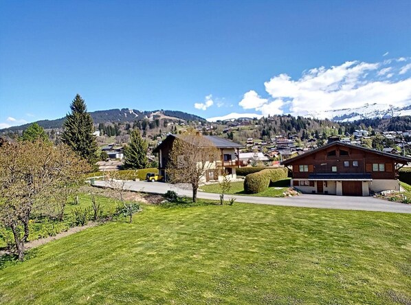 Un barrio residencial con casas, un césped cuidado y montañas al fondo.