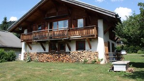 A wooden chalet with a balcony, a stone foundation, and a clear sky. - 1 Chalet Clarines (Megève)