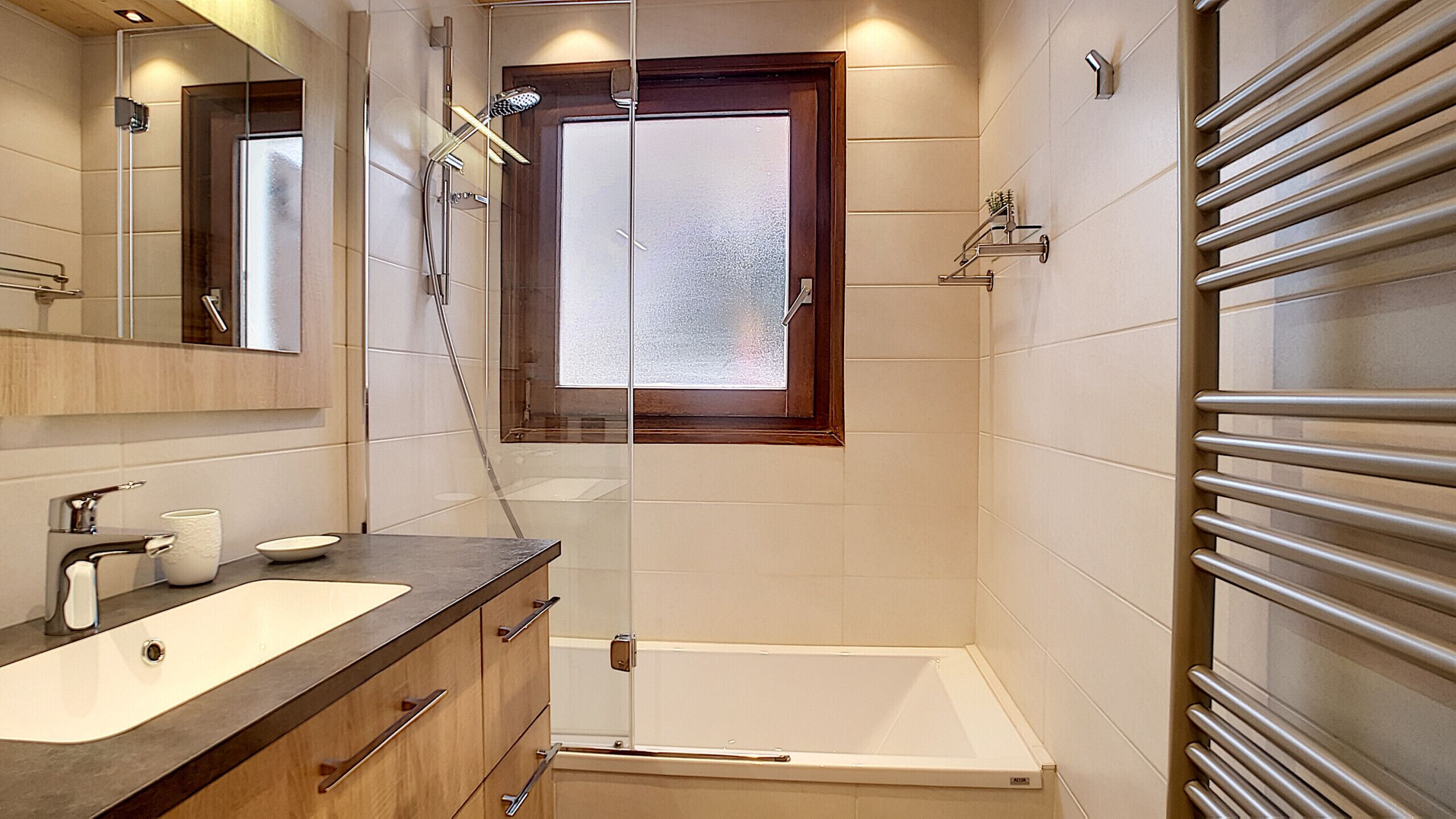 Een moderne badkamer met een badkuip, douche, wastafelmeubel en een spiegel.