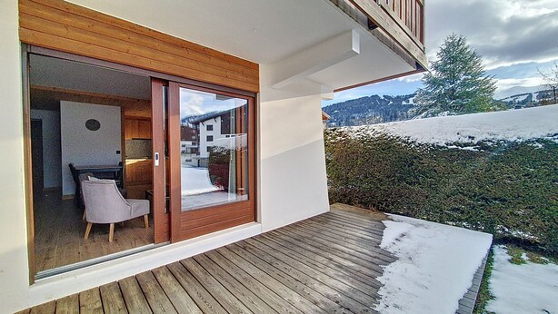 Une maison moderne dotée d’une terrasse en bois et d’une porte vitrée donnant sur un espace repas.