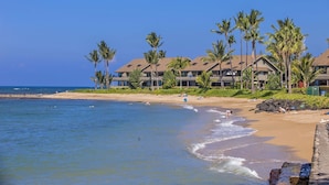 A beachfront hotel with multiple buildings, palm trees, and a sandy beach.