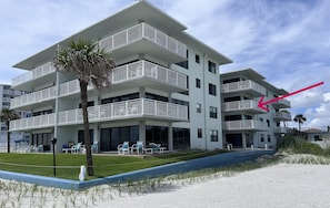 Un hotel de varios pisos con balcones, mobiliario exterior y vistas a la playa.