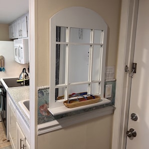 Una cocina con ventana integrada, microondas y fregadero.