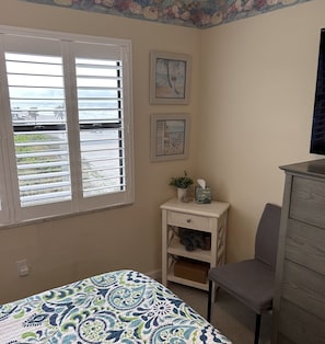 Quarto com cama, cadeira, cômoda e janela com persianas.
