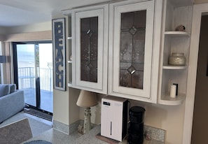 Uma cozinha moderna com armários brancos, uma cafeteira e uma pequena prateleira com objetos decorativos.