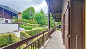 Un balcon abrité offrant une vue sur des haies soigneusement taillées et une route.
