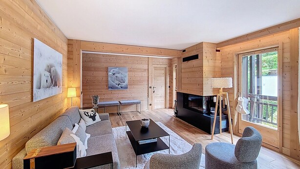 Un salon chaleureux avec une cheminée, des murs en bois, un canapé, une table basse et un banc.
