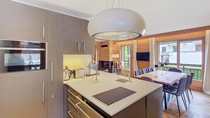 Une cuisine moderne dotée d’un îlot central, d’appareils électroménagers intégrés et d’un coin repas avec une table et des chaises.