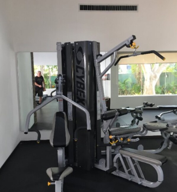 Ett gym med olika typer av träningsutrustning, inklusive en knäböjsställning och viktbänkar.