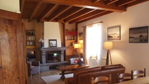 Un salon chaleureux avec une cheminée, un canapé en cuir, une table à manger en bois et des étagères à livres.