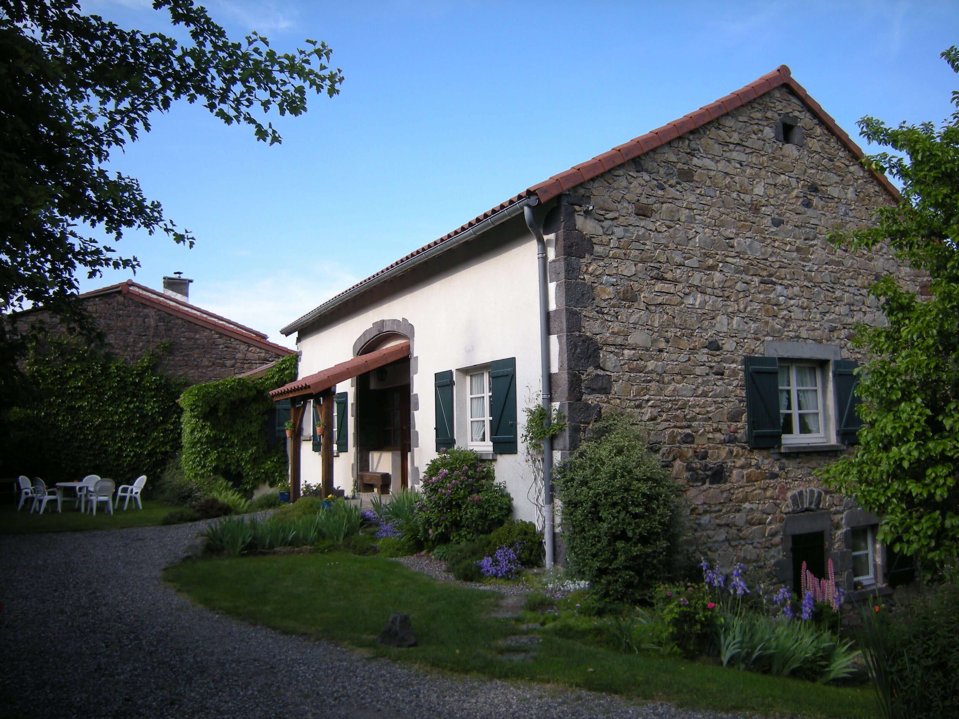 Un bâtiment en pierre doté d’un porche abrité et d’un jardin.