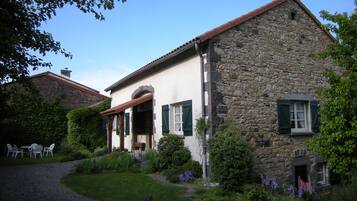 Un bâtiment en pierre doté d’un porche abrité et d’un jardin.