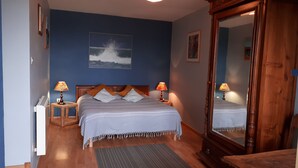 Une chambre à coucher avec un lit, deux lampes de chevet, un grand miroir et un tableau accroché au mur.