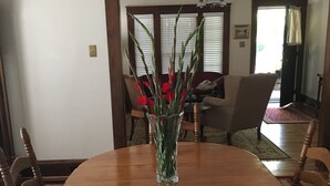Ein Esszimmer mit Holztisch, Stühlen und einer Vase mit roten Blumen.