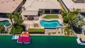A residential area with a swimming pool, boats, and a patio with outdoor furniture. - Executive Lakefront La Quinta Gem with Infinity Pool, Boats, and Casita (La Quinta)