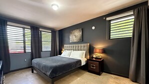 Een slaapkamer met een groot bed, een nachtkastje met een lamp en een wandklok.
