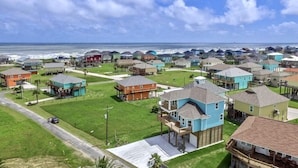 A coastal residential area with houses, a road, and a beach in the background.