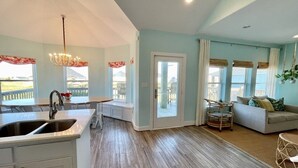 A spacious living area with a kitchen, a dining area, and a seating area with a view of the outdoors.