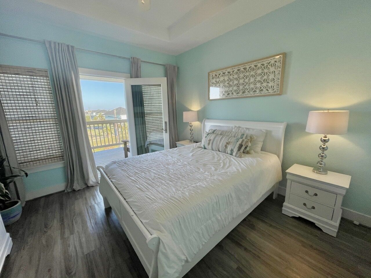 Une chambre à coucher avec un lit, des tables de chevet, une fenêtre avec des rideaux et une vue sur l’extérieur.