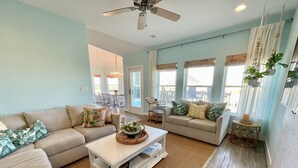A spacious living room with a high ceiling fan, two sofas, a coffee table, and a dining area with chairs.