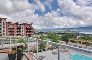 A rooftop pool area with a view of a cityscape and mountains.