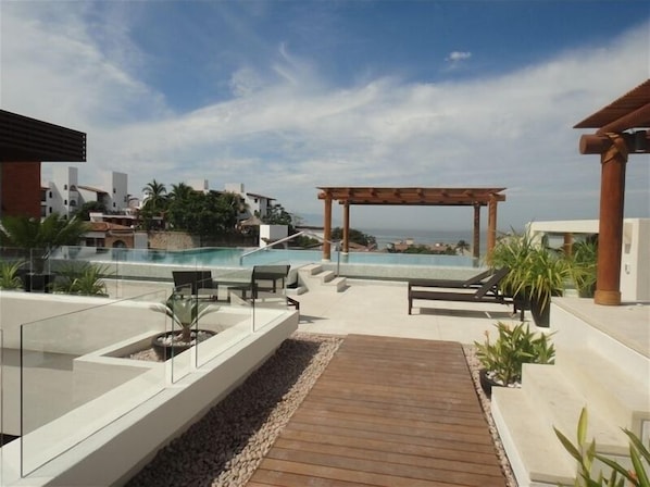 Enjoy breathtaking ocean views from this rooftop terrace featuring a glass-enclosed pool and comfortable lounge chairs.