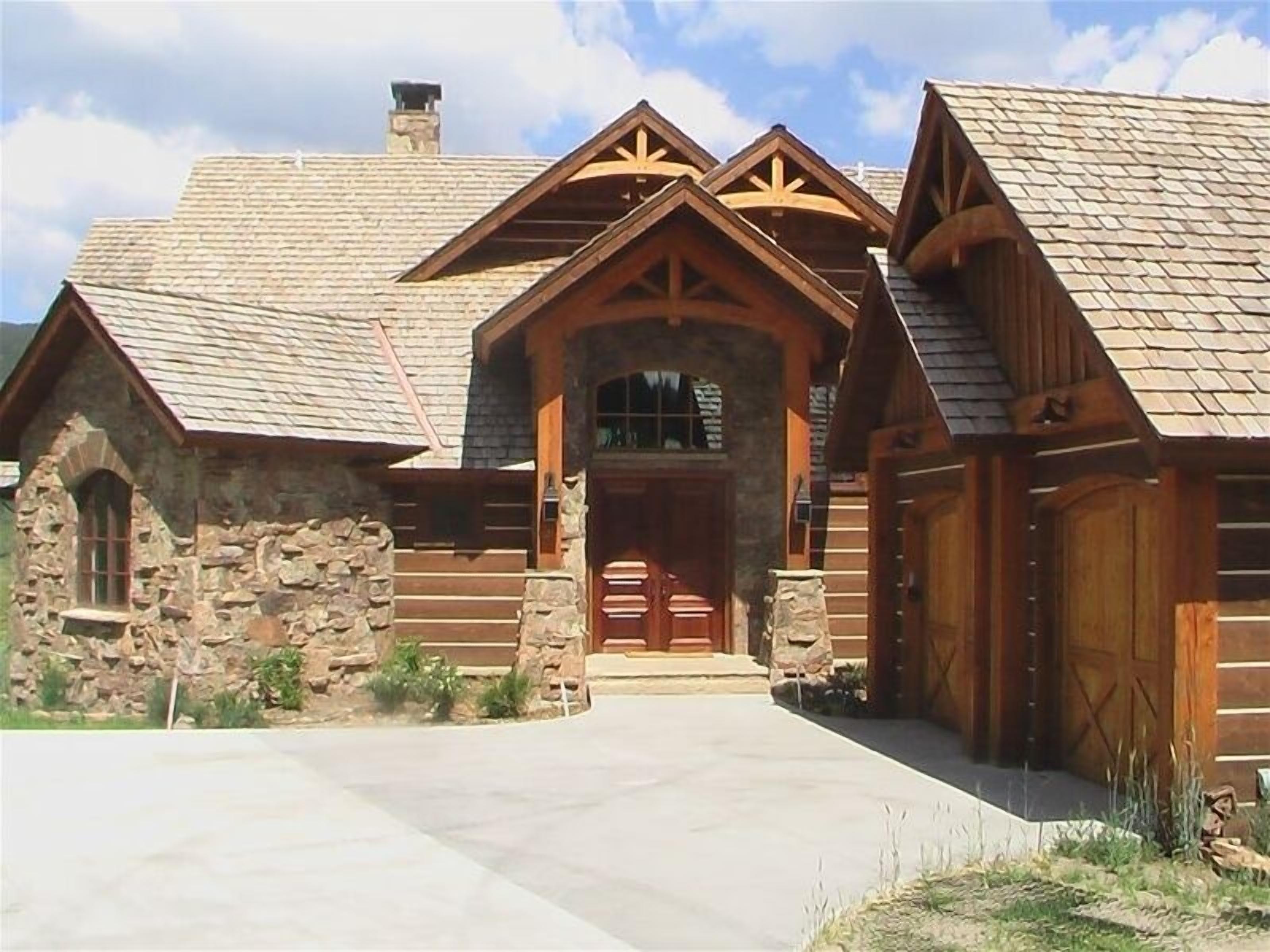 A log cabin with a stone foundation, a central entrance with a wooden door, and a chimney.