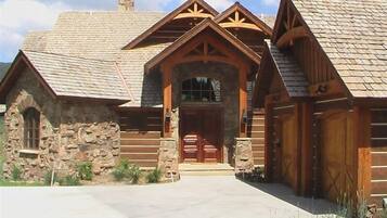 A log cabin with a stone foundation, a central entrance with a wooden door, and a chimney.