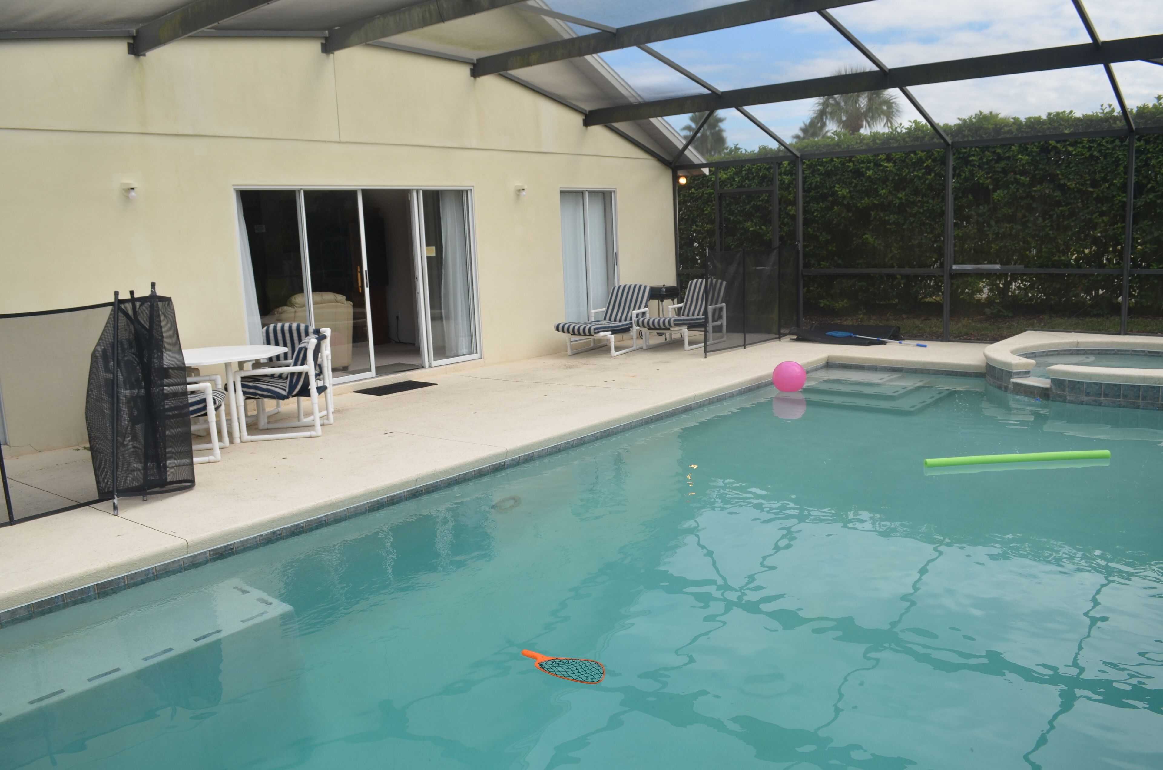 A swimming pool with lounge chairs and a covered patio area.
