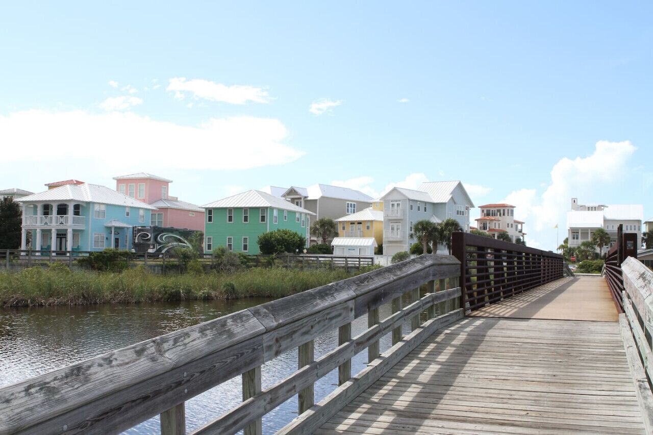 A wooden boardwalk leading to colorful houses by a body of water.