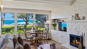 Una sala de estar acogedora con chimenea, un comedor con vistas al océano y una zona de estar confortable.