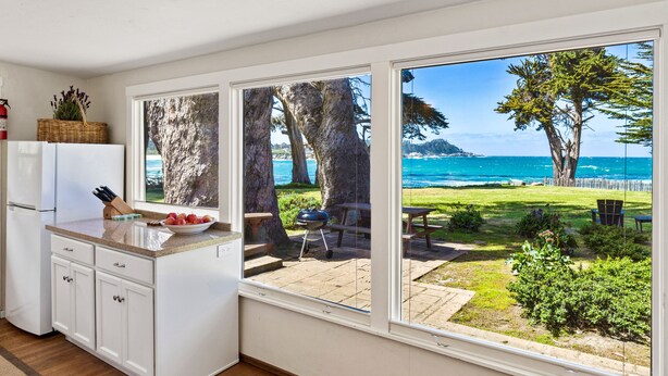 Una cocina con un ventanal grande que da a un jardín césped con vistas al mar.