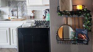 A modern kitchen with white cabinetry, a black stove, and a backsplash with a herringbone pattern. There are kitchen utensils and a kettle on the counter. - 2 bed/2 bath Townhouse on a Quiet cul de sac with backyard views and a Hot tub (Sheboygan)