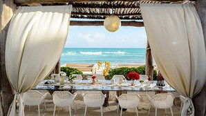 An outdoor dining area with a view of the ocean, featuring a table set with white chairs and a glass top. - Cancun Grand Mayan Master Room, 2 Adults, 2 children (Playa del carmen)