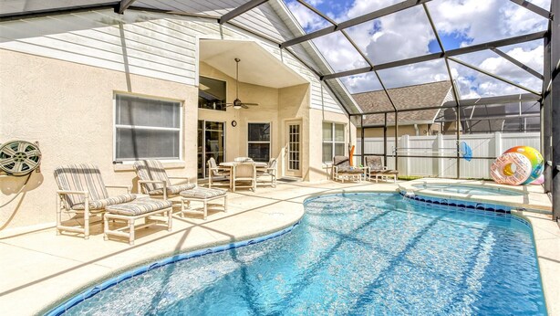 A swimming pool with lounge chairs and a covered patio area.