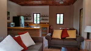 Ein Wohnzimmer mit zwei Sofas, einer Küchenzeile inklusive Mikrowelle und einem Esstisch.
