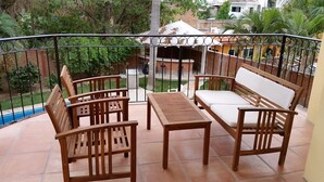 Ein Balkon mit Holzmöbeln, darunter eine Couch und Stühle sowie ein kleiner Tisch.