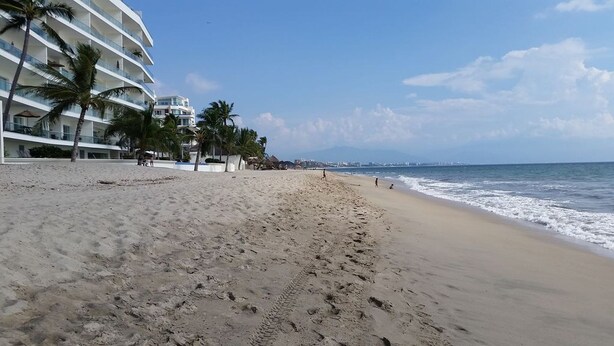 Ein Strand mit einem Hotel im Hintergrund.