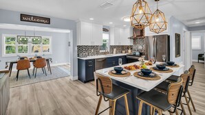 Una cocina moderna con armarios blancos, una isla central y un letrero que dice 'welcome'.