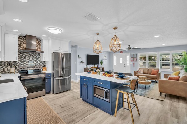 A modern kitchen with a central island, stainless steel appliances, and pendant lighting.