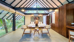 A spacious room with a high ceiling, two beds, a dining table, and a view of palm trees. - Thuduwa Camp (Rankethgama)