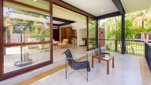 A spacious balcony with a modern design, featuring a glass wall, a wooden table, and two chairs. - Thuduwa Camp (Rankethgama)