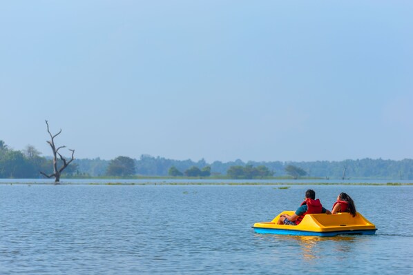 A couple on a yellow raft in a calm lake with trees in the background.