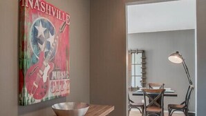Un intérieur moderne avec une table à manger en bois, un saladier posé dessus, et un mur orné d’une affiche sur laquelle on peut lire « Nashville, capitale de la musique ».