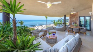 Ein geräumiger Balkon mit Meerblick, ausgestattet mit Sofas, Sesseln und einem Esstisch.