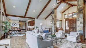A spacious living room with a large sectional sofa, a coffee table, and a dining area with a wooden table and chairs. - Breck Escape: Luxury Highlands Home, Hot Tub & Steam Shower, Sleeps 12. (Breckenridge)