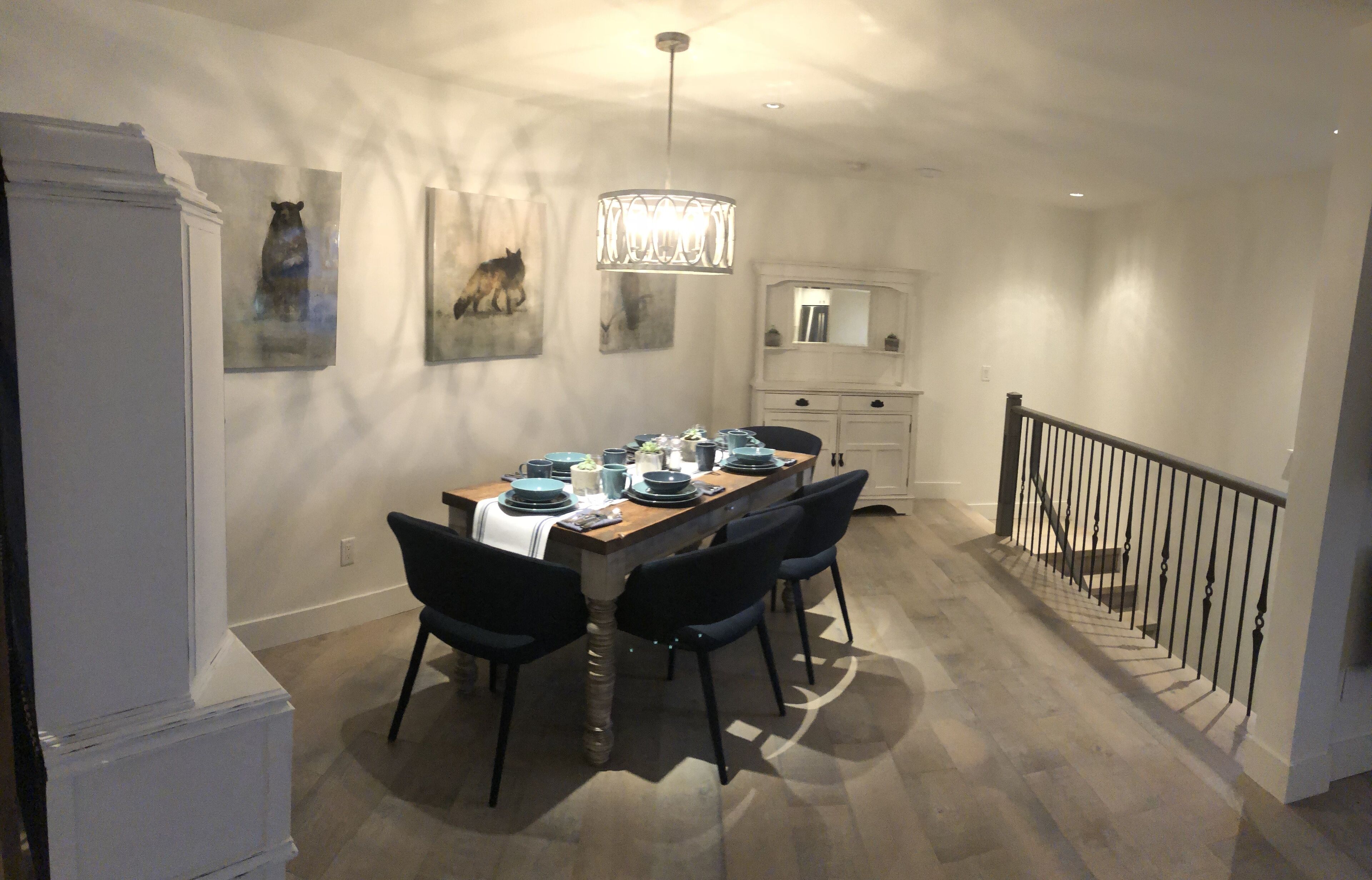 A dining area with a wooden table set for four, black chairs, and a chandelier.
