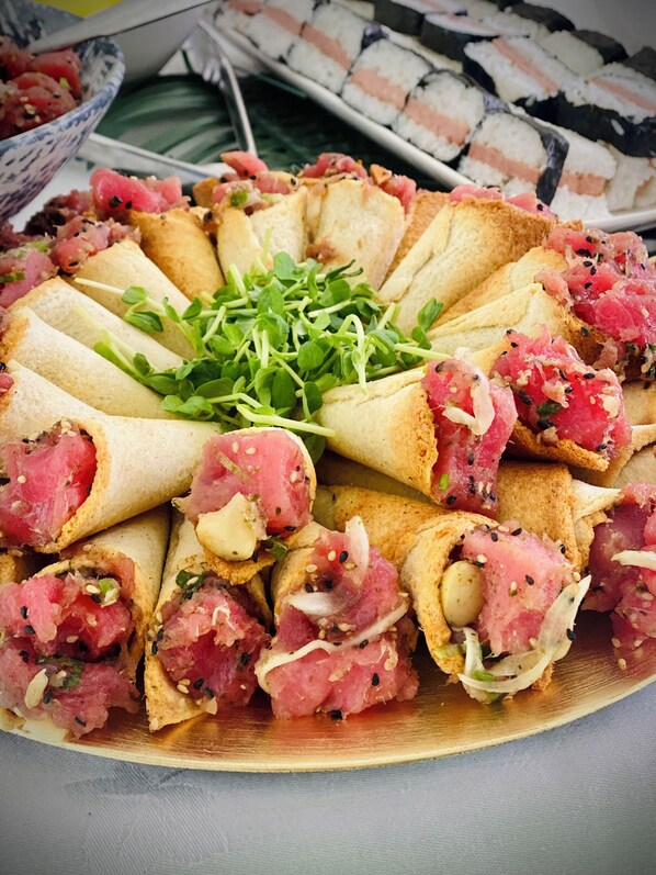A plate of sushi rolls arranged in a circular pattern with a garnish of green sprouts in the center.